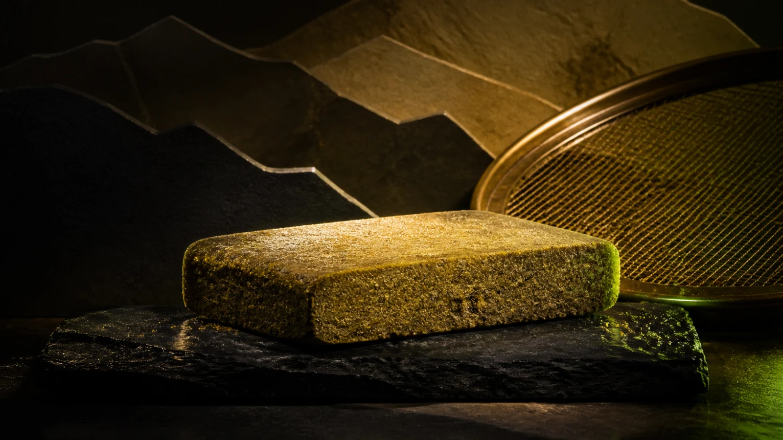 Résine CBD blonde pressée sur un plateau de tamisage dans un décor éditorial inspiré des reliefs du Rif marocain